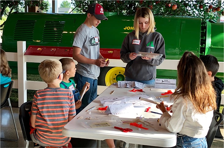 Summer camp children sitting at tables working on a craft project