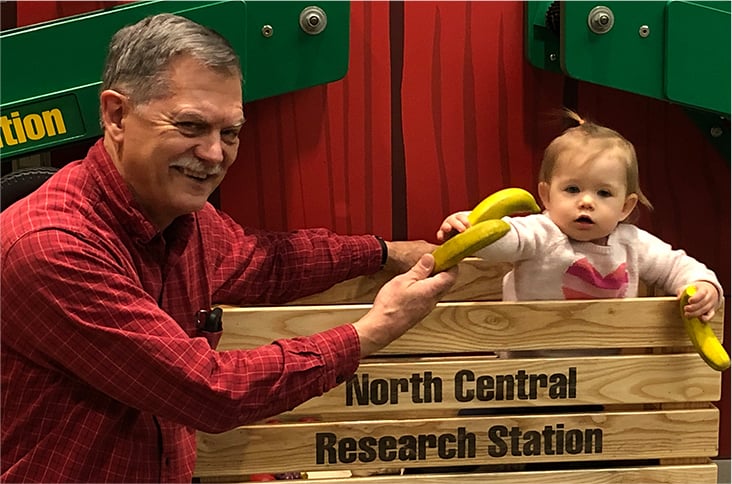 A smile child holding a banana next to a smiling adult